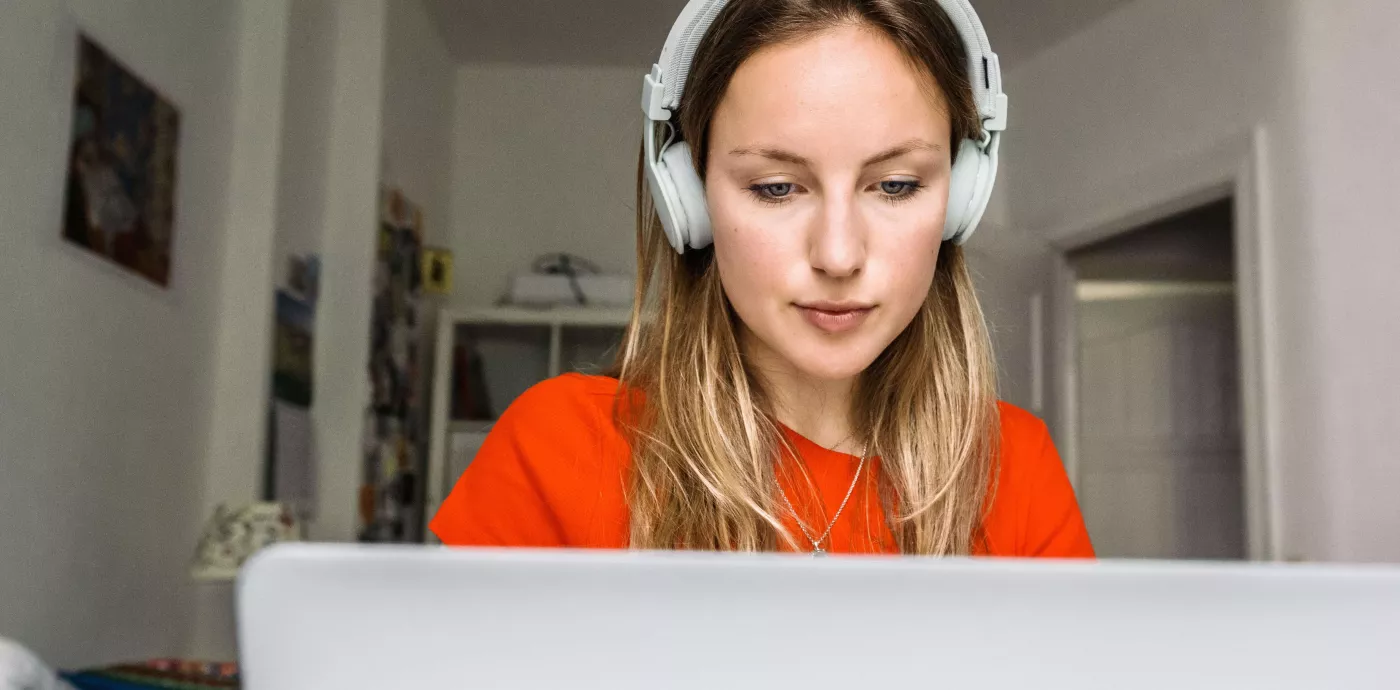 Woman looking at computer with headphones on