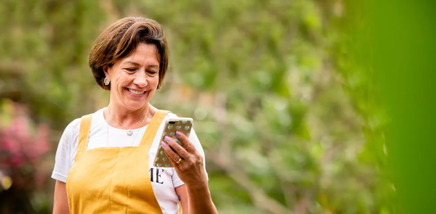 woman outside smiling while looking at phone