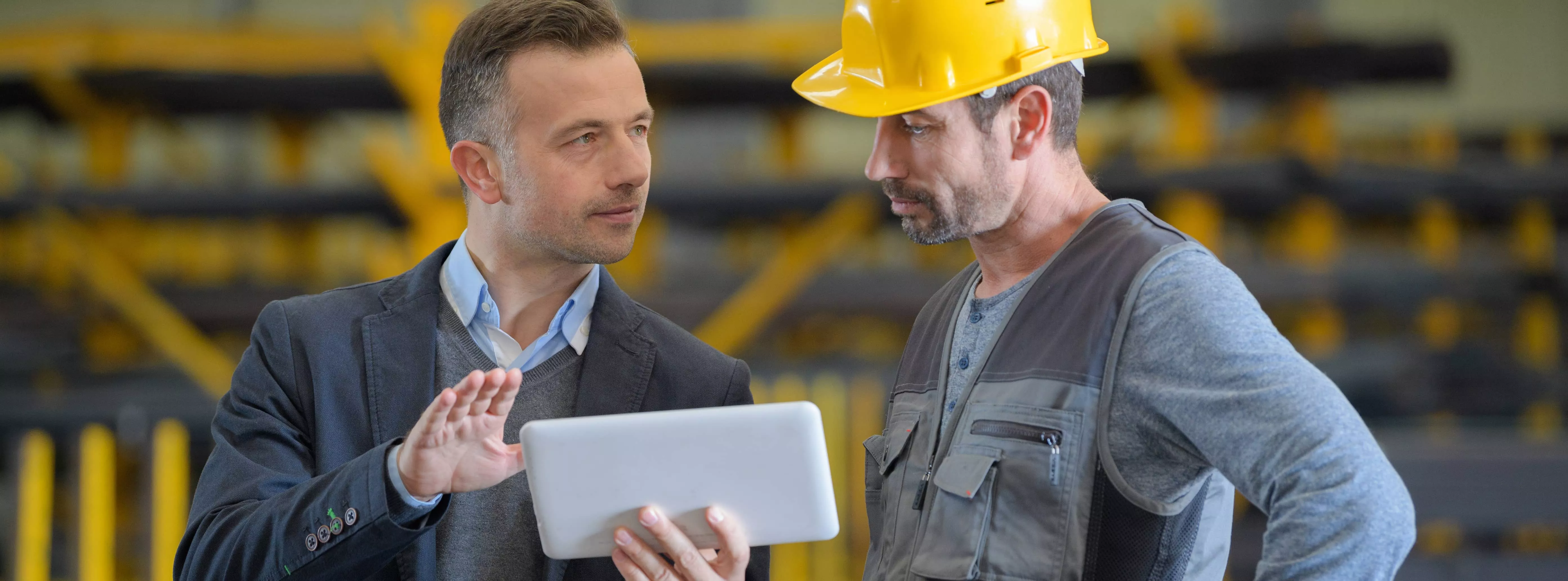 two men at construction site discussing something on a tablet 