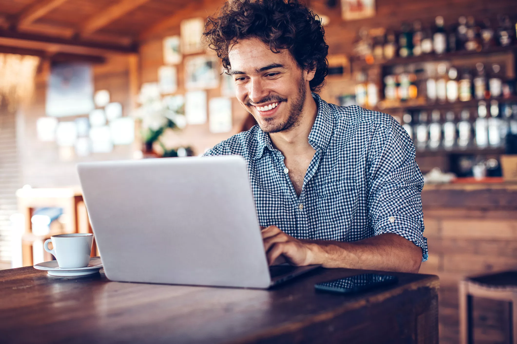 man smiling at computer while at his cafe